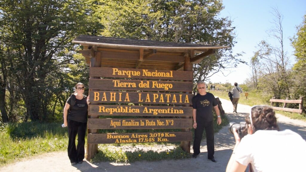 Turistas posando junto al cartel que da la bienvenida a la Bahía Lapataia, y que también anuncia el fin del la ruta 3