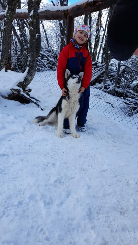 Pequeña excursionista en compañìa de un pequeño Husky en el criadero de Huskies