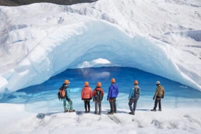 Excursionistas disfrutando de la vista de una laguna azul dentro de una cueva.