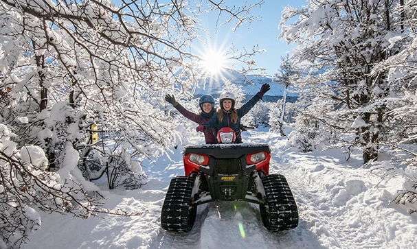 excursionistas disfrutando la Experiencia Nieve en Ushuaia a bordo de los cuatriciclos con orugas
